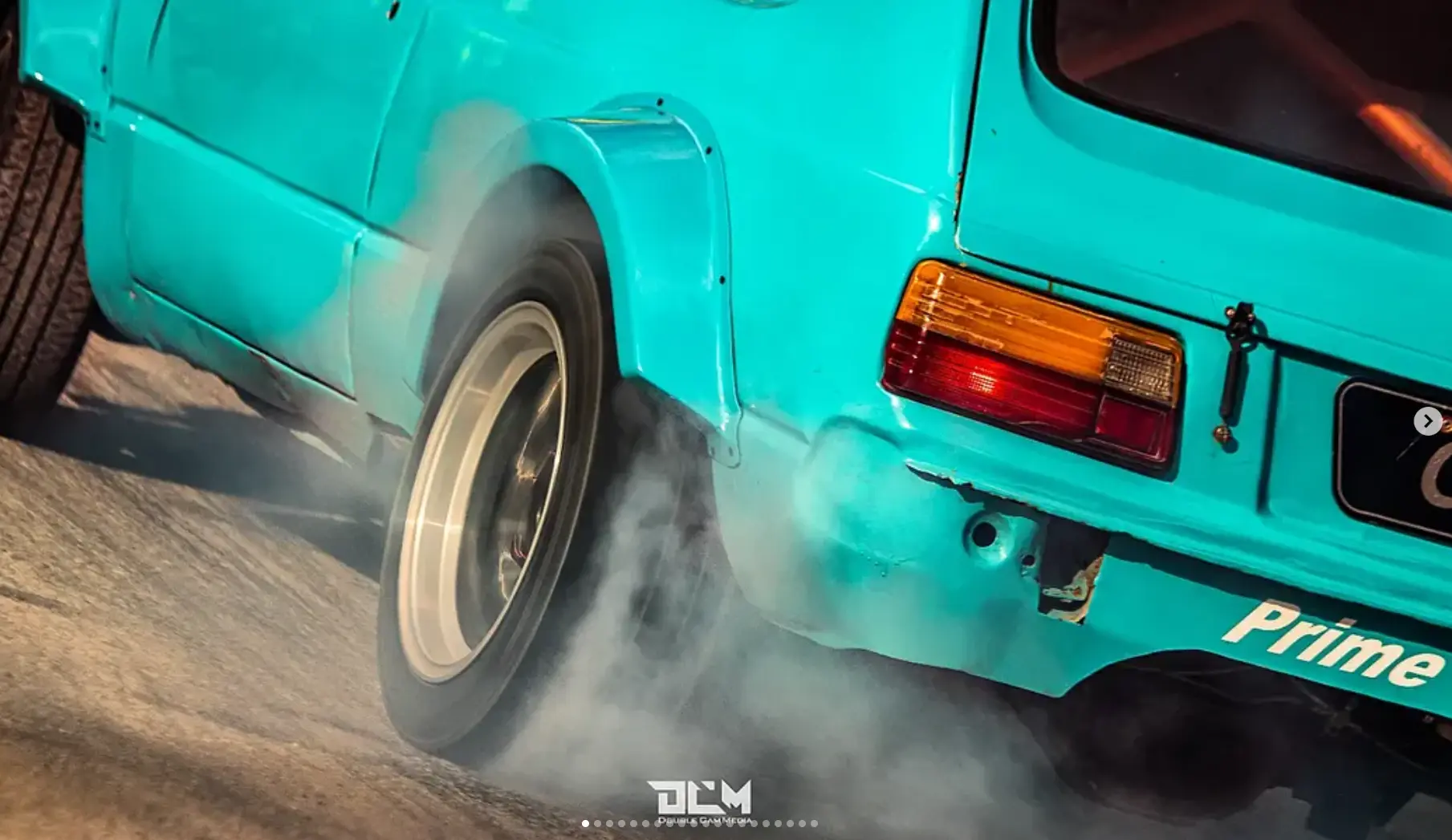 Turquoise race car performing a burnout